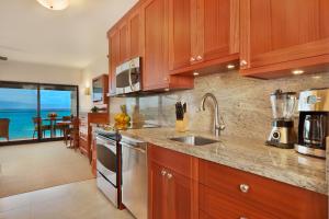 a kitchen with wooden cabinets and a view of the ocean at Napili Kai Beach Resort in Lahaina