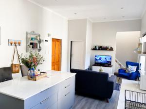 a kitchen and living room with a white counter and a couch at Stay on Main, Family Apartment in Paarl