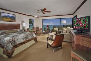 um quarto com uma cama e uma sala de estar com uma televisão em Napili Kai Beach Resort em Lahaina