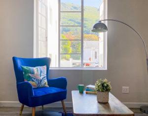 uma cadeira azul sentada numa sala de estar com uma mesa em Stay on Main, Family Apartment em Paarl