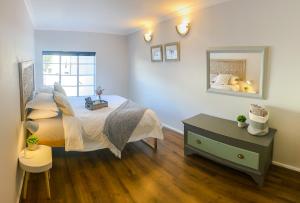 a bedroom with a large bed and a mirror at Stay on Main, Family Apartment in Paarl