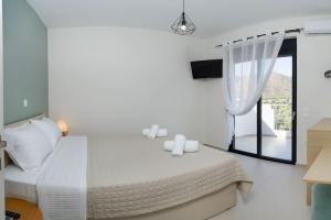 a white bedroom with a bed and a window at Lamzi's Residence in Chania Town