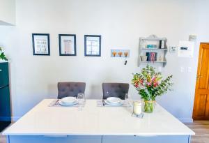 uma mesa branca com duas cadeiras e um vaso de flores em Stay on Main, Family Apartment em Paarl