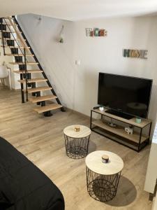 a living room with a tv and a staircase at Appartement au cœur d'Espalion Le Perchoir du Lot in Espalion