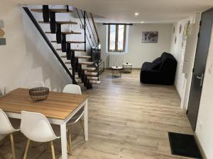 a living room with a table and a staircase at Appartement au cœur d'Espalion Le Perchoir du Lot in Espalion