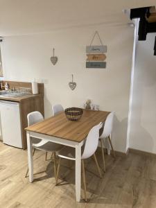 - une cuisine avec une table en bois et des chaises blanches dans l'établissement Appartement au cœur d'Espalion Le Perchoir du Lot, à Espalion
