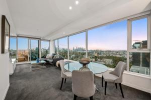 a living room with a glass table and chairs at Exclusive Stays - Seven Yarra in Melbourne