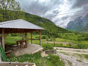 a wooden gazebo with a table and a mountain at Nature Guesthouse Vuthaj in Vusanje