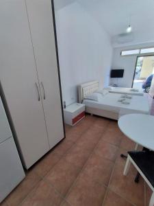 a room with a bed and a desk and a table at ARTEMISA APARTMENTS in Vlorë +2 photos