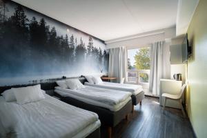 a hotel room with three beds and a window at Hotelli Uninen Loviisa in Loviisa