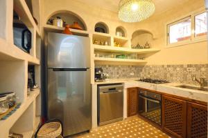 a kitchen with a stainless steel refrigerator and shelves at Riad Dar El Khir en centre ville rooftop et bassin in Marrakesh