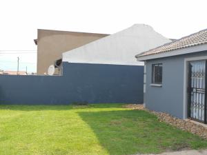a house with a blue wall and a yard at Serenity Airb&b Protea Glen in Soweto