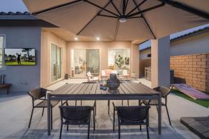 a patio with a table with chairs and an umbrella at Spectacular PGA West New Home! in La Quinta