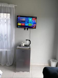a flat screen tv on a wall above a refrigerator at Serenity Airb&b Protea Glen in Soweto