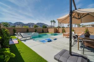 a backyard with a pool and a table and an umbrella at Spectacular PGA West New Home! in La Quinta