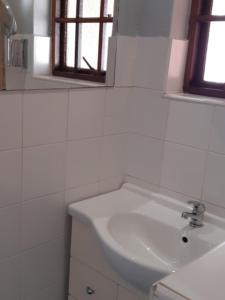 een witte badkamer met een wastafel en een spiegel bij Westlodge at Graskop B&B in Graskop