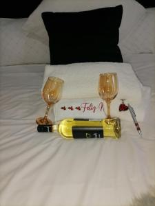 a table with a champagne bottle and two glasses on a bed at Serenity Airb&b Protea Glen in Soweto