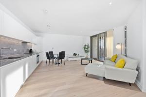 a living room with a white couch and a kitchen at Riverside View Apartments in London