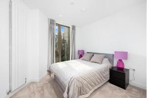 a white bedroom with a bed and a pink lamp at Riverside View Apartments in London