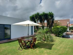 a table and chairs with an umbrella in a yard at Impeccable 1 Bed Villa in Ribeira Grande in Ribeira Grande