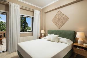 sypialnia z białym łóżkiem i oknem w obiekcie Villa Ira w mieście Chorafakia