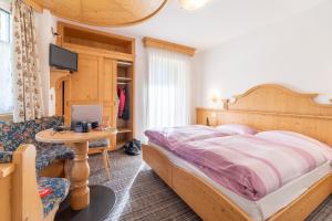 1 dormitorio con cama, mesa y TV en Albergo Canazei en Canazei