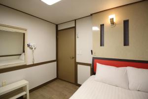 a bedroom with a bed with a red headboard and a mirror at Hangeul Guesthouse in Seoul
