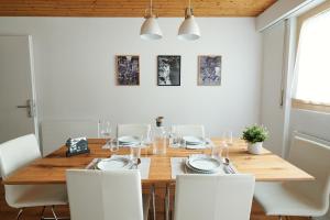 a dining room with a wooden table and white chairs at Ferienwohnung - 100m von der Talstation Aletsch Bahnen und Bahnhof Fiesch, BESTE Ausgangslage in Fiesch