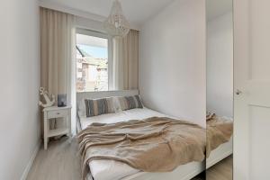 a white bedroom with a bed and a window at Flatbook Apartamenty - Sztutowo Baltic Garden in Sztutowo