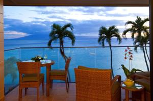 a balcony with a table and chairs and the ocean at Napili Kai Beach Resort in Lahaina