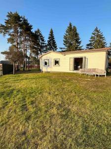 una casa blanca con un banco en un campo en Lilla Ridhuset, en Löddeköpinge