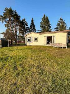 a white house with a bench in a field at Lilla Ridhuset in Löddeköpinge