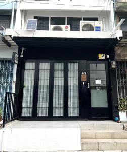 a black front door of a building with windows at PICCOLO SUKHUMVIT HOSTEL in Bangkok