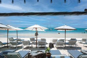 a beach with chairs and umbrellas and the ocean at Bay Beach Resort in Choeng Mon Beach