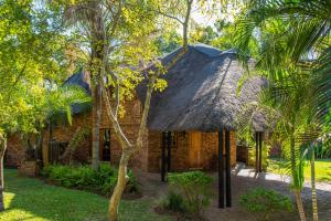 une maison au toit de chaume et une cour avec des arbres dans l'établissement Kruger Park Lodge Unit No. 209, à Hazyview