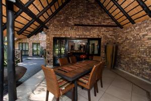 eine Terrasse mit einem Tisch, Stühlen und einer Ziegelwand in der Unterkunft Kruger Park Lodge Unit No. 209 in Hazyview