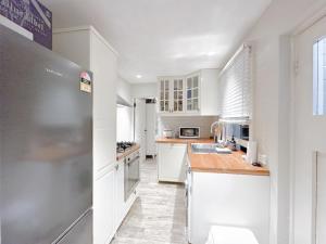 a kitchen with white cabinets and a stainless steel refrigerator at Pyrnmont Terrace & Townhouse in Sydney