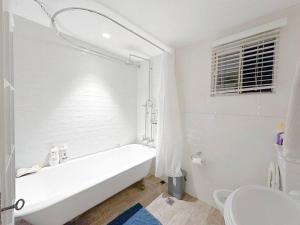 a white bathroom with a tub and a toilet at Pyrnmont Terrace & Townhouse in Sydney