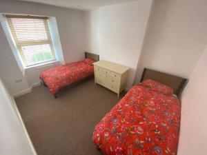 a small bedroom with two beds and a window at Ivybridge Cottage in Ivybridge