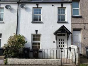 a white house with a fence in front of it at Ivybridge Cottage in Ivybridge