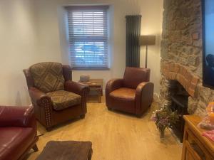 a living room with chairs and a stone fireplace at Ivybridge Cottage in Ivybridge