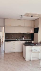 cocina con armarios blancos, fregadero y silla en Brand new, luxury beach flat, en Tsarevo