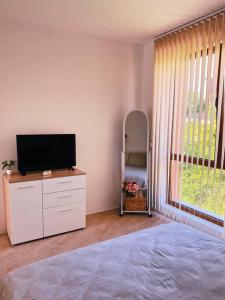 a bedroom with a flat screen tv on a dresser at Brand new, luxury beach flat in Tsarevo