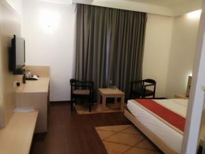 ein Hotelzimmer mit einem Bett, einem Schreibtisch und Stühlen in der Unterkunft Kingston Resort in Kānpur