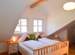 um quarto com uma cama com lençóis brancos e 2 janelas em Wenzlhof em Zwiesel