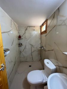a white bathroom with a toilet and a sink at Nashos Bungalows in (( Spile ))
