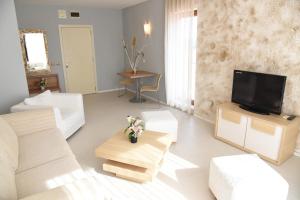 Hotel Paradise Garden في تشيرنوموريتس: غرفة معيشة بأثاث أبيض وتلفزيون بشاشة مسطحة
