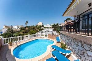 Una piscina con tumbonas al lado de un edificio. en Casa Leo holiday villa, en Mijas Costa