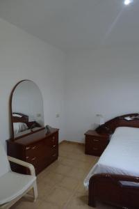 Schlafzimmer mit einem Bett, einer Kommode und einem Spiegel in der Unterkunft Swimming pool, beach and garden in Nigran in Nigrán