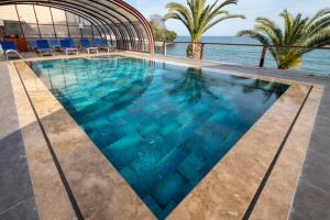 a swimming pool with blue water and palm trees at Sinop Antik Otel in Sinop